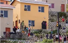  ?? ?? Members of the community look on as Red Ants officers force their way into one of the homes.