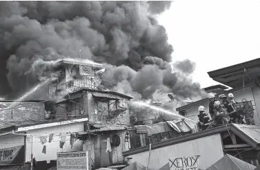  ??  ?? FIREFIGHTE­RS work at the scene of a fire in an informal settlement in Manila on Tuesday. Ted ALJIBE / AFP