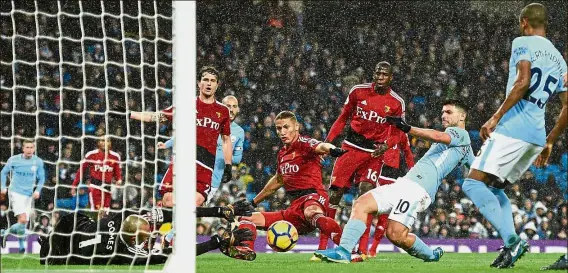  ?? AFP ?? Surging with Sergio: Manchester City’s Sergio Aguero (second from right) scoring the third goal past Watford goalkeeper Heurelho Gomes in the English Premier League match at the Etihad on Tuesday. City won 3-1. —