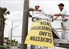  ?? JENNIFER REYNOLDS/THE GALVESTON COUNTY DAILY NEWS VIA AP ?? Workers remove banners from a post in front of Landry’s Seafood House in Galveston, Texas, on Monday as residents and business prepare for Tropical Storm Nicholas.