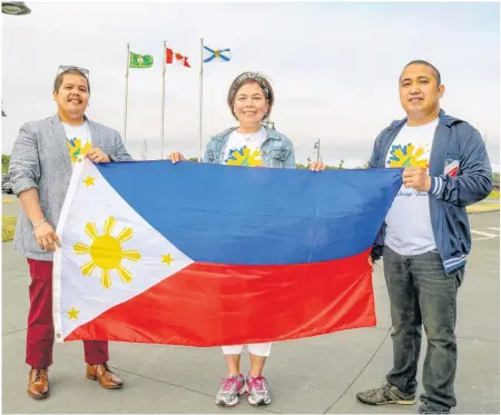  ?? JESSICA SMITH • CAPE BRETON POST ?? From left, Julius Garcio, Elena Hernandez Young and Jon Morales hold up the flag of the Philippine­s to celebrate Filipino Heritage Month.