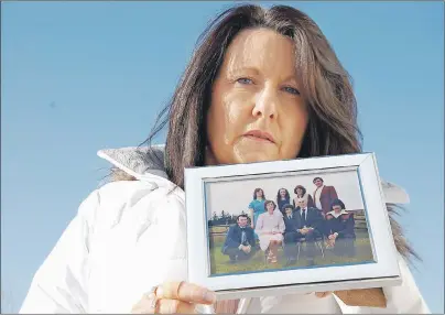  ?? +*. %": 5$ .&%*" ?? Cheryl Doherty holds the last family photo ever taken of her parents, her and her six siblings. Her parents did not want another family photo taken after daughter Theresa Ann Gregory disappeare­d in 1982. Back row, from left, are Gregory, Doherty,...