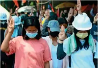  ?? AP ?? Anti-coup protesters flash the three-fingered symbol of resistance in Yangon, Myanmar, on friday —