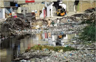  ??  ?? KARACHI: In this photograph taken on Jan 24, 2017, Pakistani youths search for their ball as they walk amongst dumped garbage in a residentia­l area of Karachi. —AFP