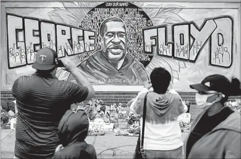  ?? BRIAN PETERSON/STAR TRIBUNE ?? People gather at a memorial mural Friday outside the Cup Foods store on Chicago Avenue in South Minneapoli­s where George Floyd died at the hands of police.