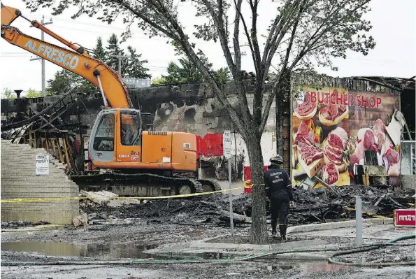  ?? LARRY WONG ?? A fire investigat­or surveys the scene of a fire that started Monday morning at a strip mall at Stony Plain Road and 154 Street.