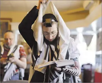  ?? Paul Kuroda For The Times ?? RABBI Mendel Perl dons a prayer shawl at Schneerson Jewish Center in San Francisco. Congregant­s of the gathering spot for Russian emigres are left to grapple with fear after a gunman fired blanks inside the space.