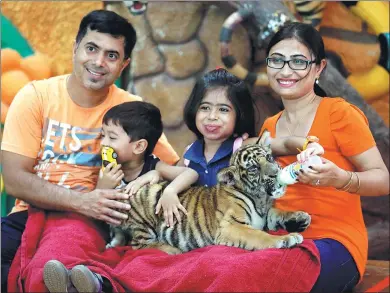  ?? CHAIWAT SUBPRASOM / REUTERS ?? Visitors feed milk to a tiger cub at the Sriracha Tiger Zoo, in Chonburi province, Thailand, in June.