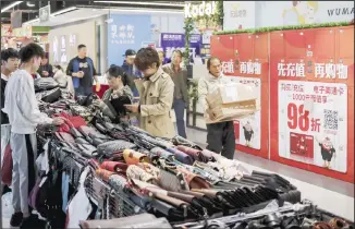  ??  ?? A worker carrying boxes of goods walks by women selecting handbags at a commercial building in Beijing, on Oct 18. China’s economic growth sank to a 26-year low in the latest quarter amid pressure from a trade war with
Washington, adding to a deepening slump that is weighing on global growth. (AP)