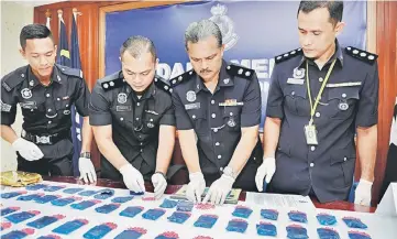  ??  ?? Roslan (second right) showing the seized pills during a press conference in Kuala Terengganu yesterday. — Bernama photo