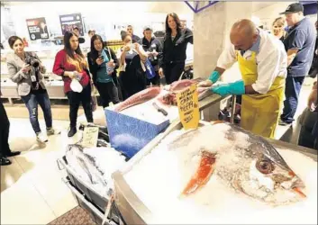  ?? Mel Melcon Los Angeles Times ?? GILBERT AYARD draws a crowd as he fillets an ahi tuna at the newly opened Whole Foods store at 8th Street and Grand Avenue in downtown L.A. Whole Foods forecast sales growth of 3% to 5% this fiscal year.
