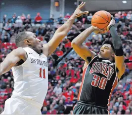  ?? JAKE ROTH/ USA TODAY ?? UNLV guard Jovan Mooring prepares to shoot over San Diego State guard D’Erryl Williams during the second half of the Rebels’ 77-64 Mountain West loss Sunday at Viejas Arena in San Diego. The Rebels have dropped seven straight games and are tied for...