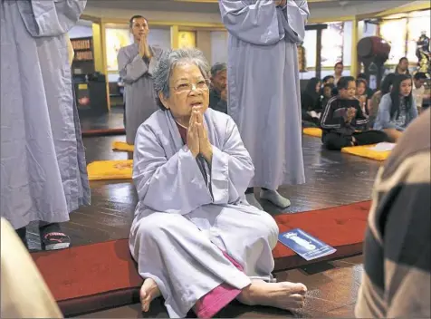  ?? Nate Guidry/Post-Gazette photos ?? Nguyen Thi Hoa of Dormont prays Sunday during the dedication of new Vietnamese Buddhist temple in Dormont. The opening of the temple has been at least a couple of years in the making, including making over a former church into a temple.