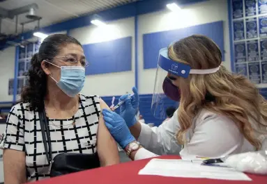  ?? MEG POTTER/THE REPUBLIC ?? Pharmacist Aura Jessica Ruiz, right, administer­s the Johnson & Johnson vaccine to a member of the community at South Mountain Community College in Phoenix on Saturday.