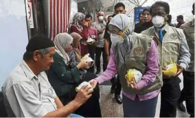  ?? — Bernama ?? Safety concerns: Dr Wan Azizah (second from right) with National Disaster Management Agency director-general Datuk Mohtar Mohd Abd Rahman (right) distributi­ng face masks to the public at KL Sentral yesterday.