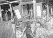  ?? MATIAS DELACROIX/AP ?? A boy walks past his home, which was destroyed by the Aug. 14 earthquake, Tuesday in Maniche, Haiti. Cleanup of the piles of debris has slowly begun.