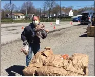  ?? MACOMB DAILY FILE PHOTO ?? Terry Revere, a volunteer with Forgotten Harvest, picks up bags of potatoes to distribute to Mount Clemens residents outside of the Jermaine Jackson Community Center.