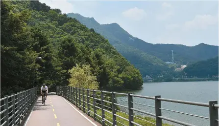 ?? Courtesy of Korea Tourism Organizati­on ?? A man rides a bicycle on a trail that surrounds Lake Uiam in Chuncheon, Gangwon Province.