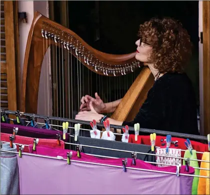  ??  ?? STRIKING A CHORD: A woman plays the harp in front of drying laundry on the balcony of her home in Turin