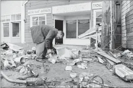  ?? Associated Press ?? A MAN SORTS through debris after the 1964 tidal wave that hit Crescent City, Calif. In 2011, ample warning helped the city evacuate residents before a tsunami.