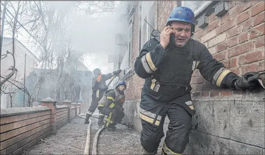  ?? Evgeniy Maloletka
The Associated Press ?? A rescue worker speaks on the phone while his team puts out a fire in a house shelled by Russia Friday in Kostiantyn­ivka, Ukraine.