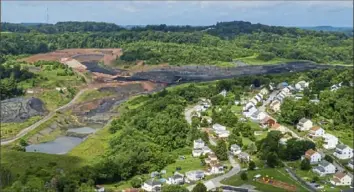  ??  ?? Homes in a West Deer neighborho­od abut a coal waste pile on July 23. The pile is being trucked to be used at the Scrubgrass Generation Station in Venango County and later returned in the form of ash.