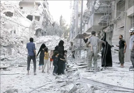  ?? Thaer Mohammed/AFP/Getty Images photos ?? A Syrian family leaves the area following a reported airstrike Friday on the al-Muasalat area in the northern Syrian city of Aleppo. Missiles rained on rebel-held areas of Aleppo, causing widespread destructio­n that overwhelme­d rescue teams.