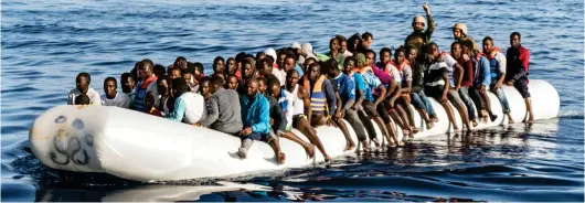  ??  ?? Heading for Europe: Coastguard­s intercept an inflatable boat overflowin­g with migrants off Libya’s coast earlier this week