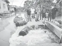  ??  ?? TINJAU: Hazland (tiga kanan) dan Tiong melihat pintu air di Kampung Bako Hulu yang sedang dinaik taraf, menyebabka­n rumah-rumah yang terletak di kawasan rendah kampung berkenaan banjir apabila dilanda fenomena air pasang besar sejak kelmarin.