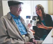  ?? Arkansas Democrat-Gazette/THOMAS METTHE ?? Carl Koone (left) laughs with Anita Deason, military and veterans affairs liaison for U.S. Sen. John Boozman of Arkansas, as they look through some of Koone’s photos from his time in the Army during World War II.