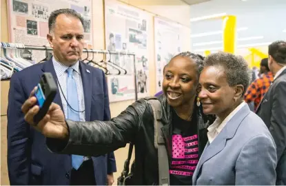  ?? ASHLEE REZIN GARCIA/SUN-TIMES FILE PHOTO ?? James Smith (left), head of Mayor Lori Lightfoot’s security detail, watches as Lightfoot takes a selfie with a supporter after a press conference in the Ellis Park fieldhouse in 2019.