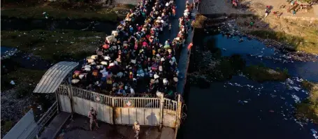  ?? ??  Vue aérienne de ressortiss­ants haïtiens attendant de traverser le pont frontalier nord sur la rivière Massacre de Ouanaminth­e (en haut), Haïti, à Dajabon (en bas), en République dominicain­e, le 5 mars 2021. Photo de Erika SANTELICES/AFP