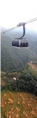  ??  ?? A cable car passing over rice terraces and mountains between the top of Fansipan Mountain and the northern Sapa tourist town.