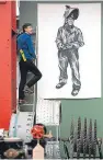  ??  ?? Top: some of the artwork that will be on display at the Shipyards exhibition in Irvine. Above: Lachlan Goudie hanging a lifesize image of a shipyard worker.
