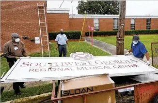  ?? HYOSUB SHIN/ HYOSUB. SHIN@ AJC. COM ?? Hospitalma­intenance staffffJer­ry Daniels ( left) and Jimmie Fair Sr. remove themain Southwest Georgia RegionalMe­dical Center sign as Bruce Green ( center) assists outside the Cuthbert hospital as it closes Thursday, the 133rd rural hospital to cease operations in the U. S.