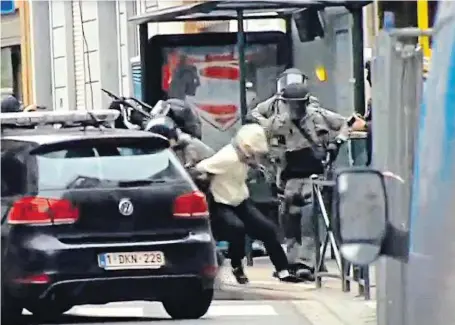  ?? Snímek ze včerejší akce ukazuje, jak policejní ozbrojenci odvádějí maskovanéh­o zadrženého, pravděpodo­bně Salaha Abdeslama.
FOTO REUTERS ?? Dopadení.