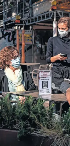  ??  ?? Una pareja, protegida con mascarilla­s, disfruta de una terraza en el primera