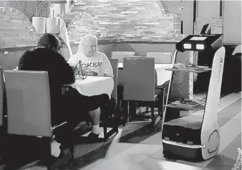  ?? STOCKER/SOUTH FLORIDA SUN SENTINEL PHOTOS MIKE ?? Troy and Vicki Charlton get their food delivered by a robot at Mr. Q Crab House, a Hollywood seafood restaurant.