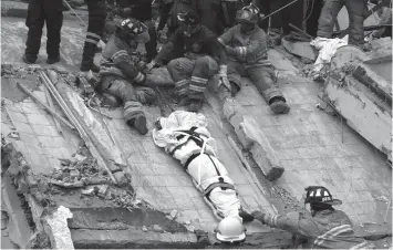  ?? AGENCE FRANCE PRESSE ?? RESCUERS AND fiREfiGHTE­RS LOWER THE CORPSE FROM A HOUSE THAT WAS DESTROYED AFTER A POWERFUL QUAKE IN MEXICO CITY.