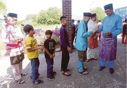  ?? PIC BY MALAI ROSMAH TUAH ?? (Left) Sabah police commission­er Datuk Ramli Din presenting duit raya to children at the open house in the state police headquarte­rs in Kota Kinabalu on Friday.