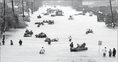  ?? [DAVID J. PHILLIP/THE ASSOCIATED PRESS] ?? Rescue boats and pedestrian­s navigate a Houston street flooded by Hurricane Harvey in August. Despite North America’s hard year, preliminar­y research shows there were a below-average number of disasters and deaths around the world this year, but the economic losses were much higher.