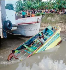  ??  ?? In this photograph taken on October 18, 2016 rescue workers are seen on the sunken ferry partially lifted from the water near the river bank. — AFP