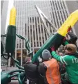  ??  ?? Employees of the American Christmas company set up the Christmas display in front of 1221 Avenue of the Americas in midtown Manhattan.