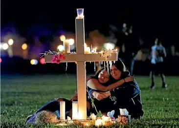  ?? AP ?? In this February
15, 2018 file photograph, people comfort each other as they sit and mourn at one of
17 crosses, after a candleligh­t vigil for the victims of the shooting at Marjory Stoneman Douglas High School, in Parkland, Florida on February 14,
2018. President Joe Biden has called on Congress to strengthen gun laws on this year’s anniversar­y of the shooting.