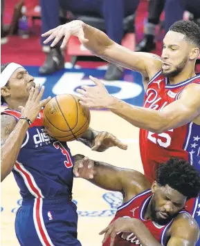  ?? SLOCUM/AP MATT ?? Washington Wizard Bradley Beal, left, cannot get a shot past the Philadelph­ia 76ers’ Ben Simmons, top, and Joel Embiid during Wednesday season opener in Philadelph­ia.