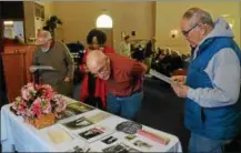  ??  ?? Members of Our Lady of the Rosary look at old pictures taken during church services.