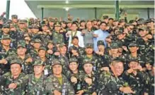  ??  ?? MANILA: This file photo taken on October 4, 2016 shows Philippine President Rodrigo Duterte (C) gesturing with clenched fists for a photo session during a “talk to the troops” visit to meet military personnel. —AFP