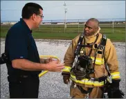  ?? ?? Chief Duane Stitzel (left), Dayton Internatio­nal Airport Fire Department, talks with Jerry Hopewell, 788th Civil Engineer Squadron Fire Department firefighte­r and emergency medical technician, on Oct. 5 after one of his crews extinguish­ed a live training fire at WrightPatt­erson Air Force Base. Hopewell was among the Wright-Patt firefighte­rs who monitored and advised DIA counterpar­ts.