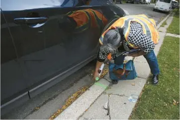  ?? MICHAEL BLACKSHIRE/CHICAGO TRIBUNE ?? Volunteer Dulce Garduno spray-paints the sidewalk a location for a potential future tree on a block in Little Village on Oct 13.