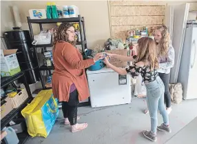  ?? MATHEW MCCARTHY WATERLOO REGION RECORD ?? Julie Sawatzky gets help from her daughters Aleena Gut, 10, centre, and Olivia Gut, 12, while packing items for hampers.